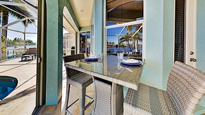 A modern kitchen with a glass-top table, wicker chairs, and a view of the outdoors.
