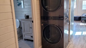 Een compacte, donkere was- en droogcombinatie in een kamer met houten vloeren en lichte muren.