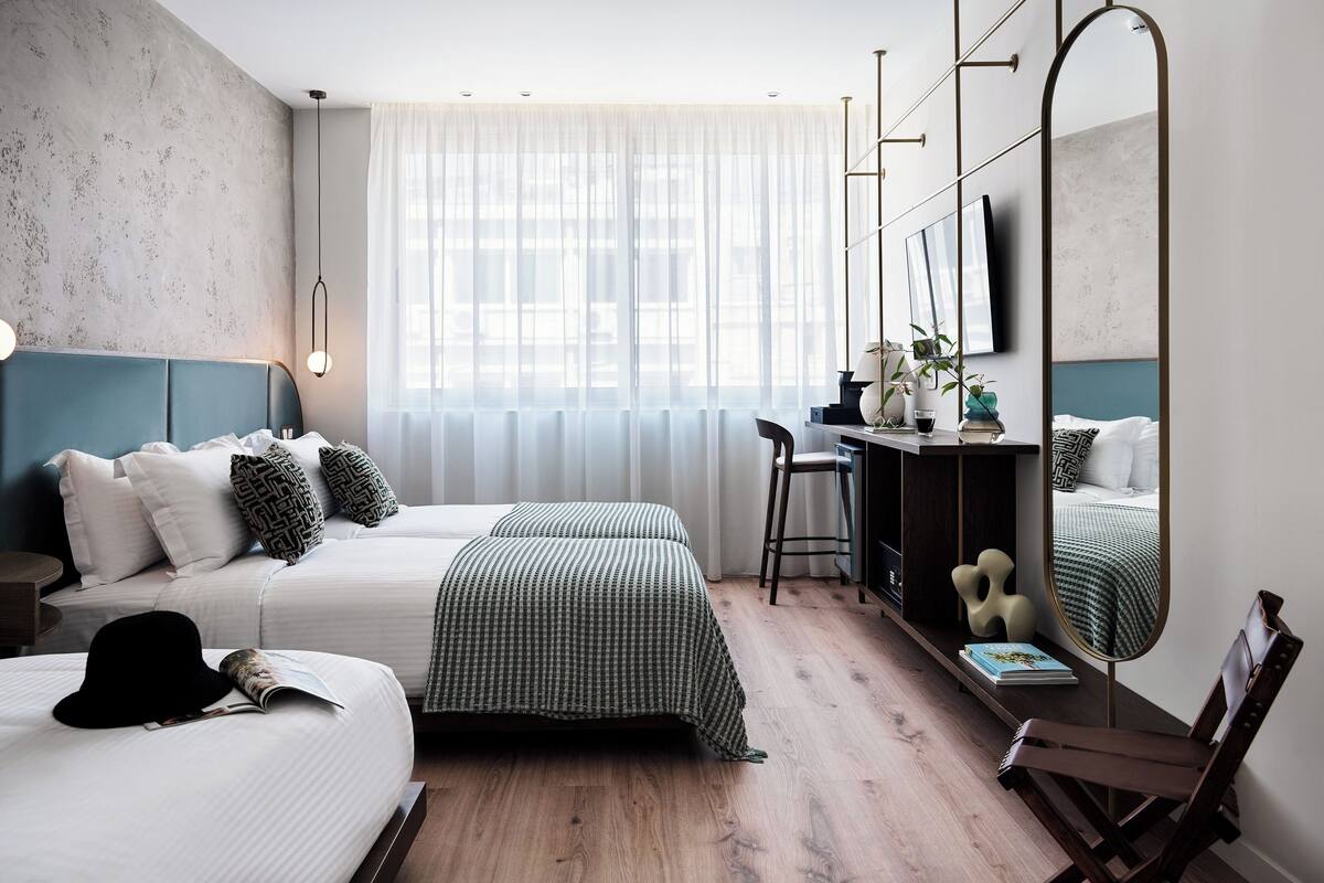 A modern hotel room with a large bed, a desk, and a mirror.