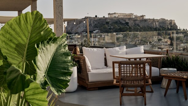 Une terrasse sur le toit offrant une vue sur un bâtiment historique, aménagée avec un canapé, des chaises et une table.