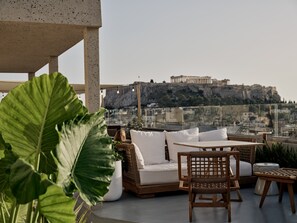 A rooftop terrace with a view of a historic building, furnished with a sofa, chairs, and a table. - The Lekka Hotel & Spa (Athens)