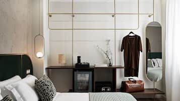 A modern hotel room with a bed, bedside table, dresser, mirror, and a hanging light fixture.