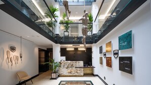 Eine moderne Lobby mit einer zentralen Sitzecke, einem Empfangsbereich und einer Glaskonstruktion als Treppe.