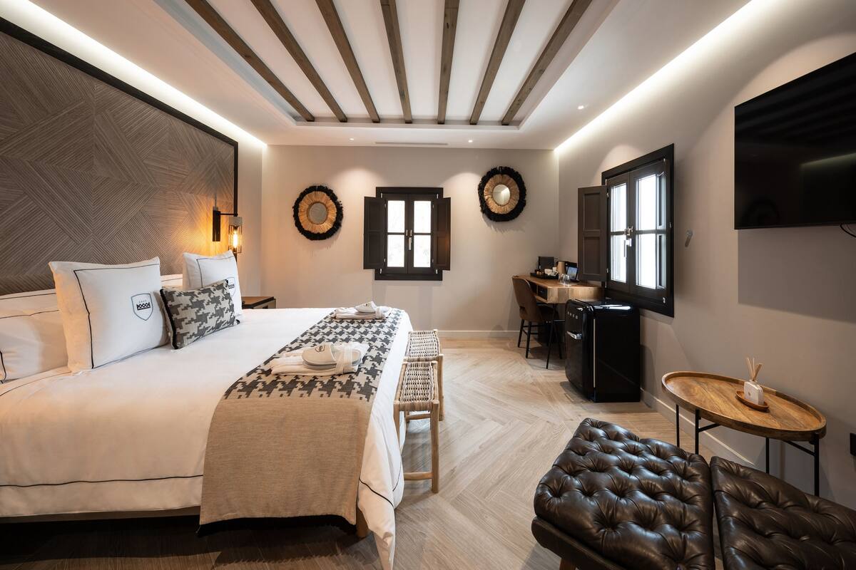 A modern hotel room with a bed, desk, and seating area.