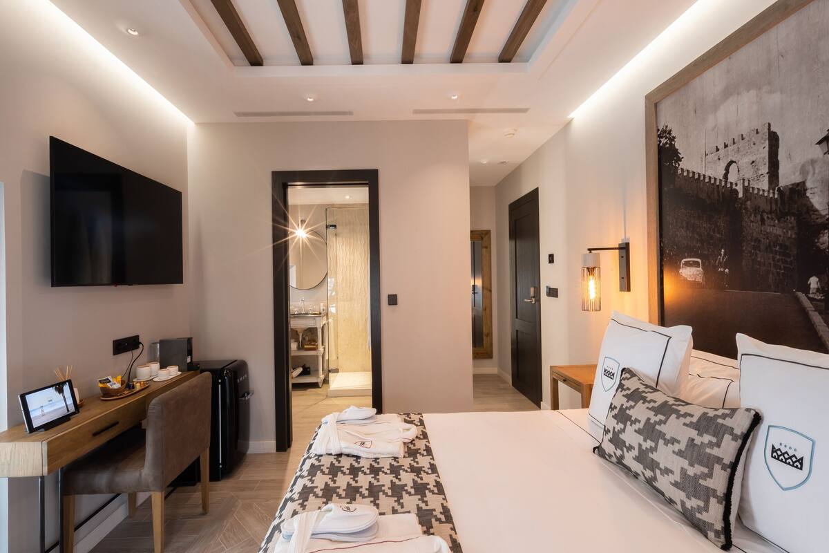 A modern hotel room with a bed, desk, and a large wall mural.