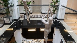 Eine moderne Lobby mit einer zentralen Treppe, Glasgeländern und Blumentöpfen.