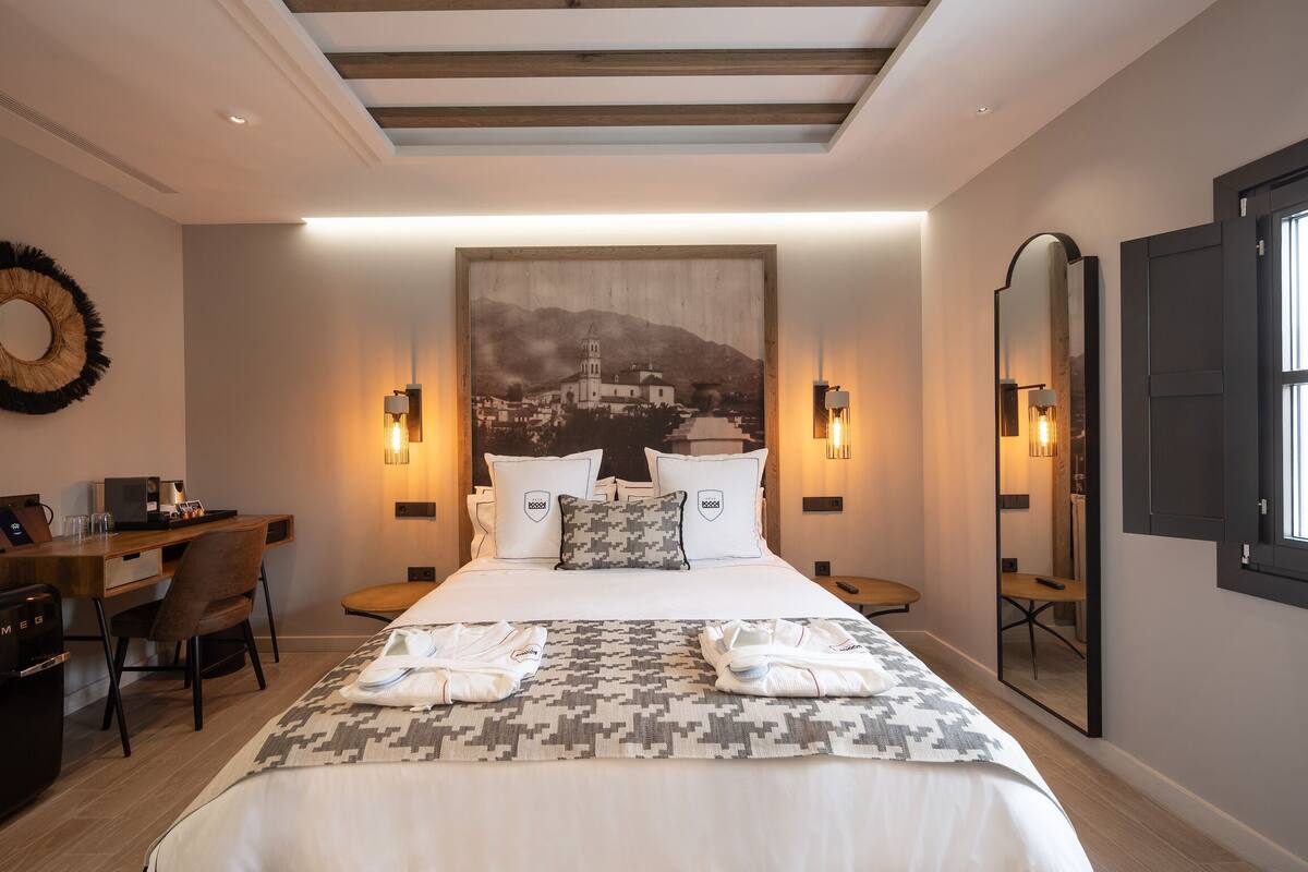 A hotel room with a bed, bedside tables, a desk, and a chair.