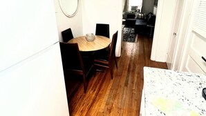 Una cucina compatta con zona pranzo, pavimento in legno, ventilatore a soffitto e frigorifero.