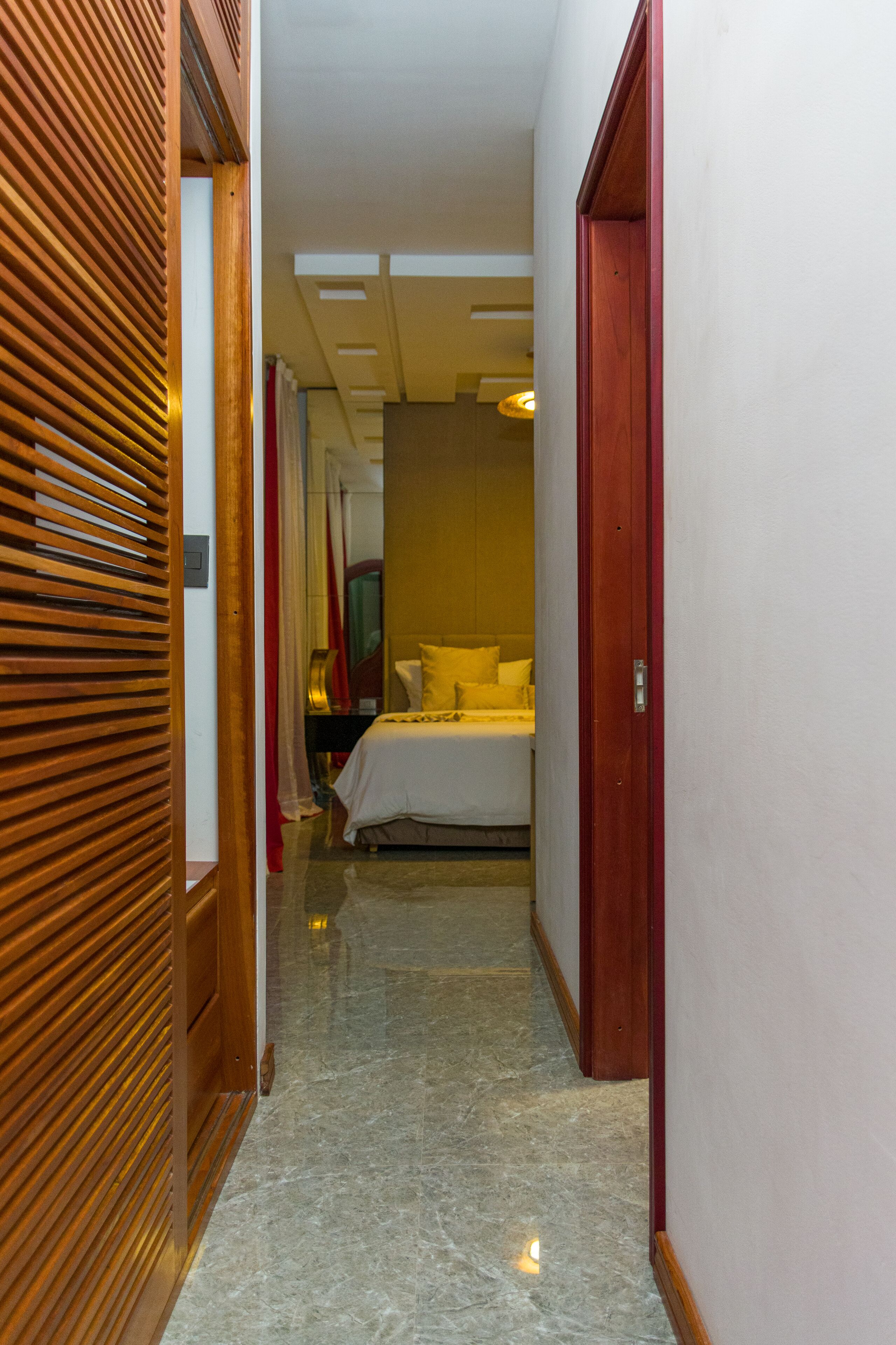 Un pasillo de hotel con una cama, puertas de madera y un espejo.