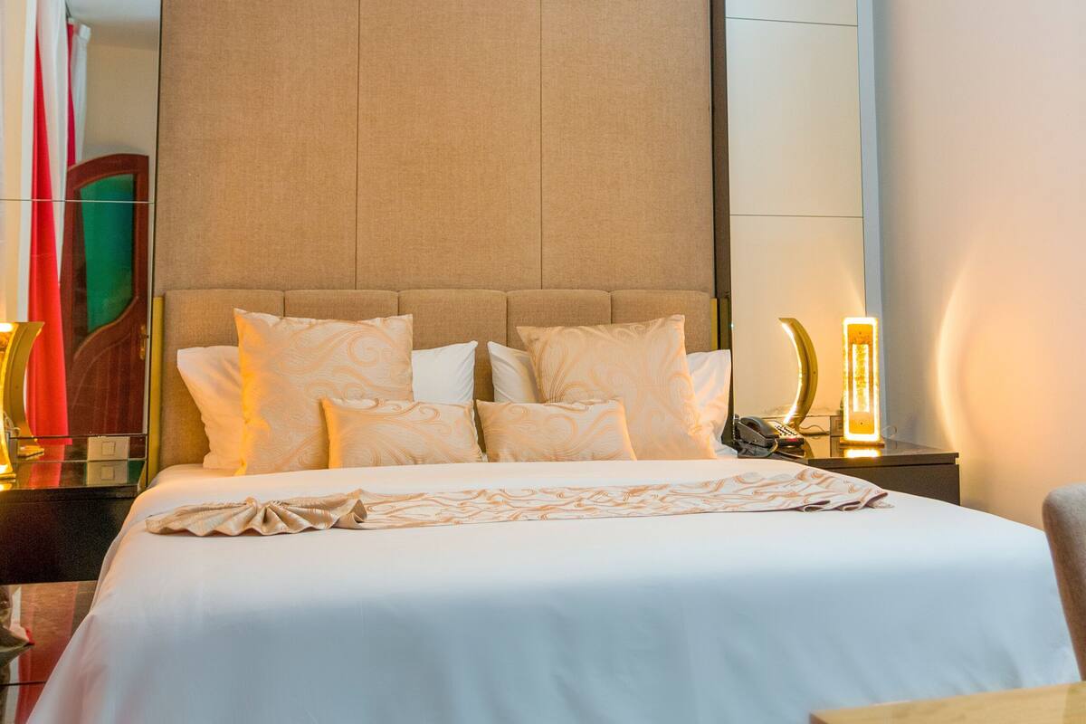 Habitación de hotel con una cama grande, una mesita de noche y una lámpara en el techo.