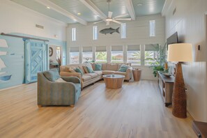 A spacious living area with a large window, a ceiling fan, and a view of the outside.