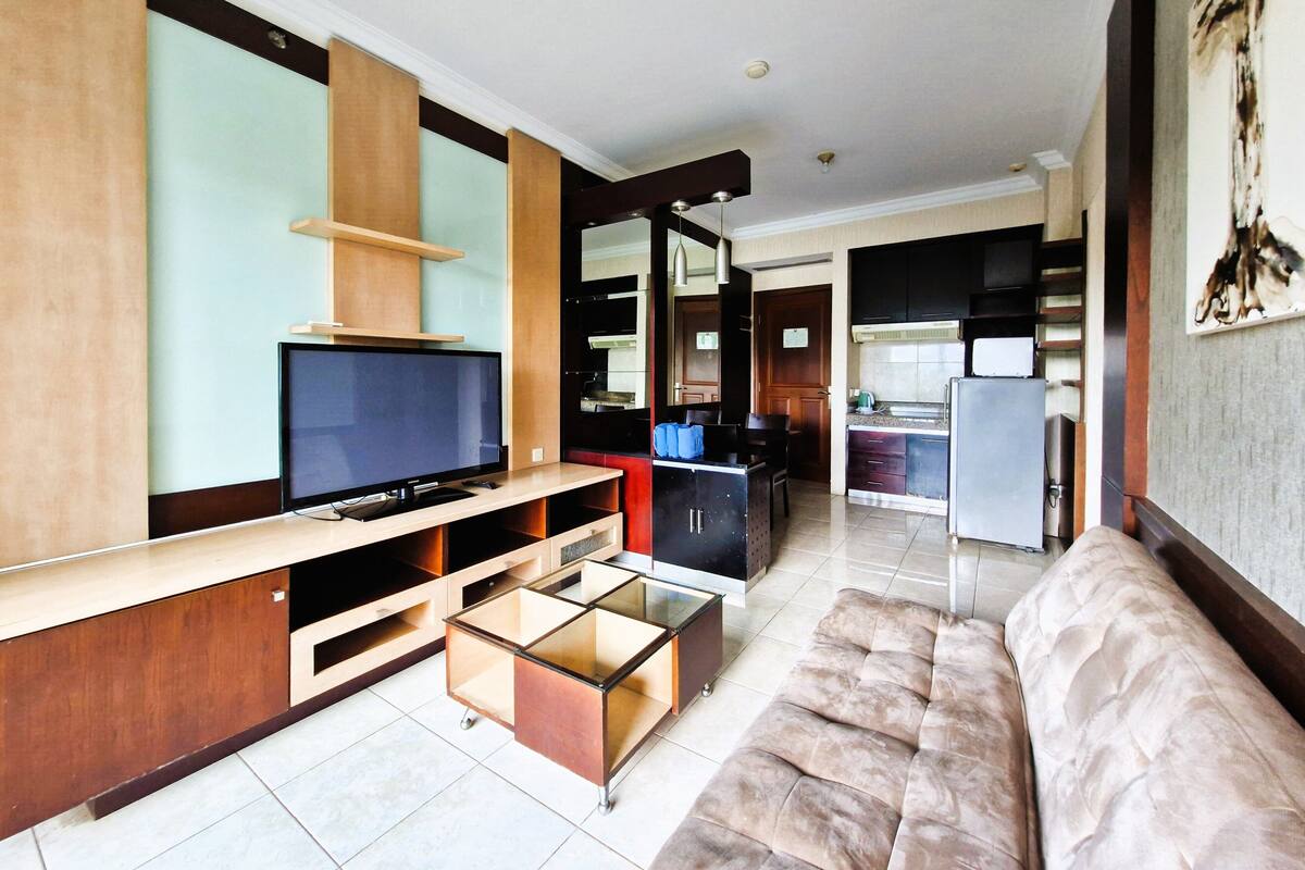 Een moderne woonkamer met een flatscreen televisie, een glazen salontafel en een comfortabele bank.