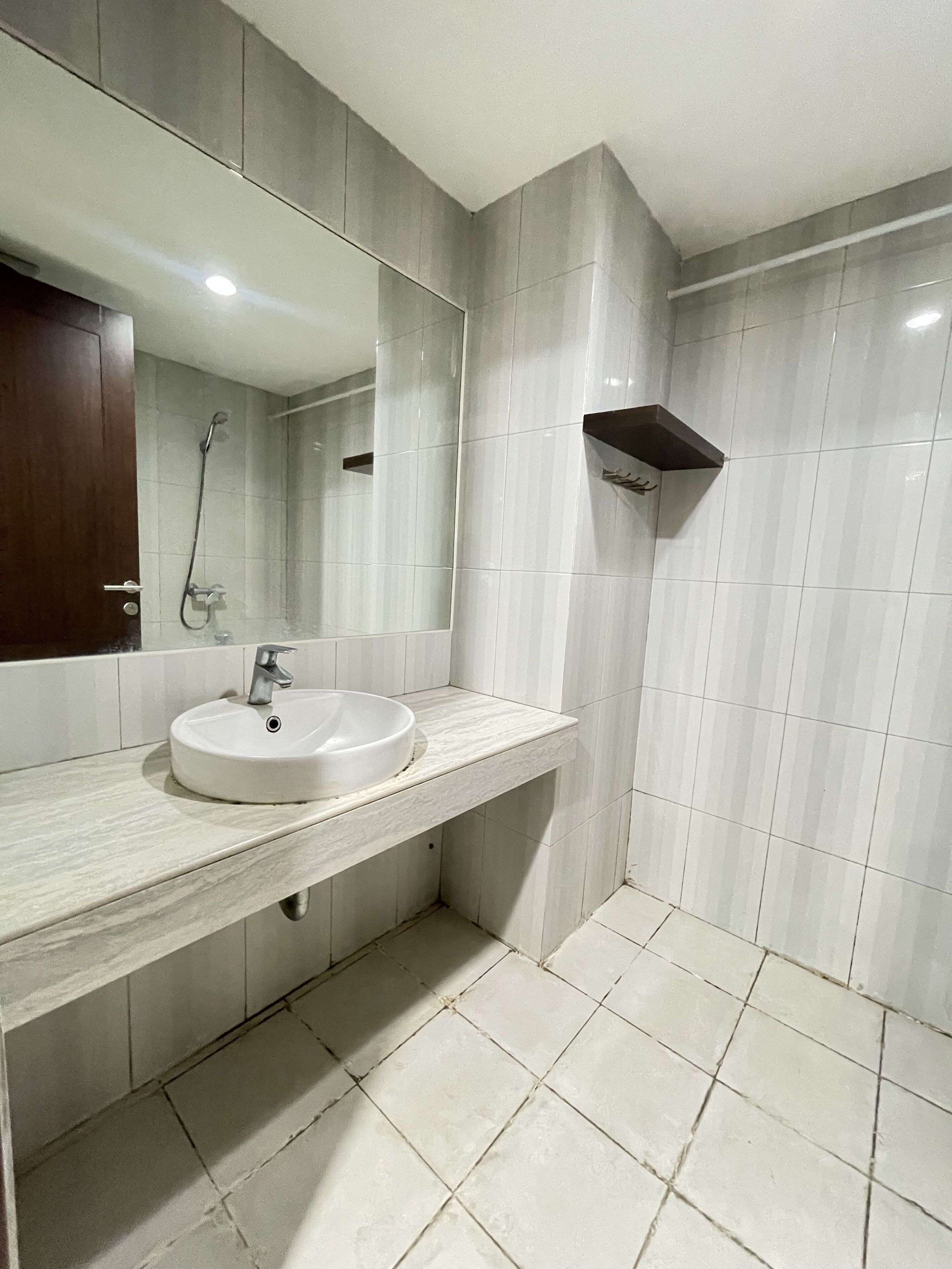 Un baño con lavamanos, espejo, ducha y paredes con azulejos.