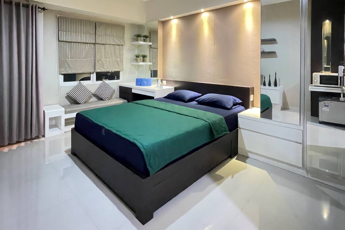 Een moderne slaapkamer met een groot bed, nachtkastjes, een spiegel en een inbouwkast.