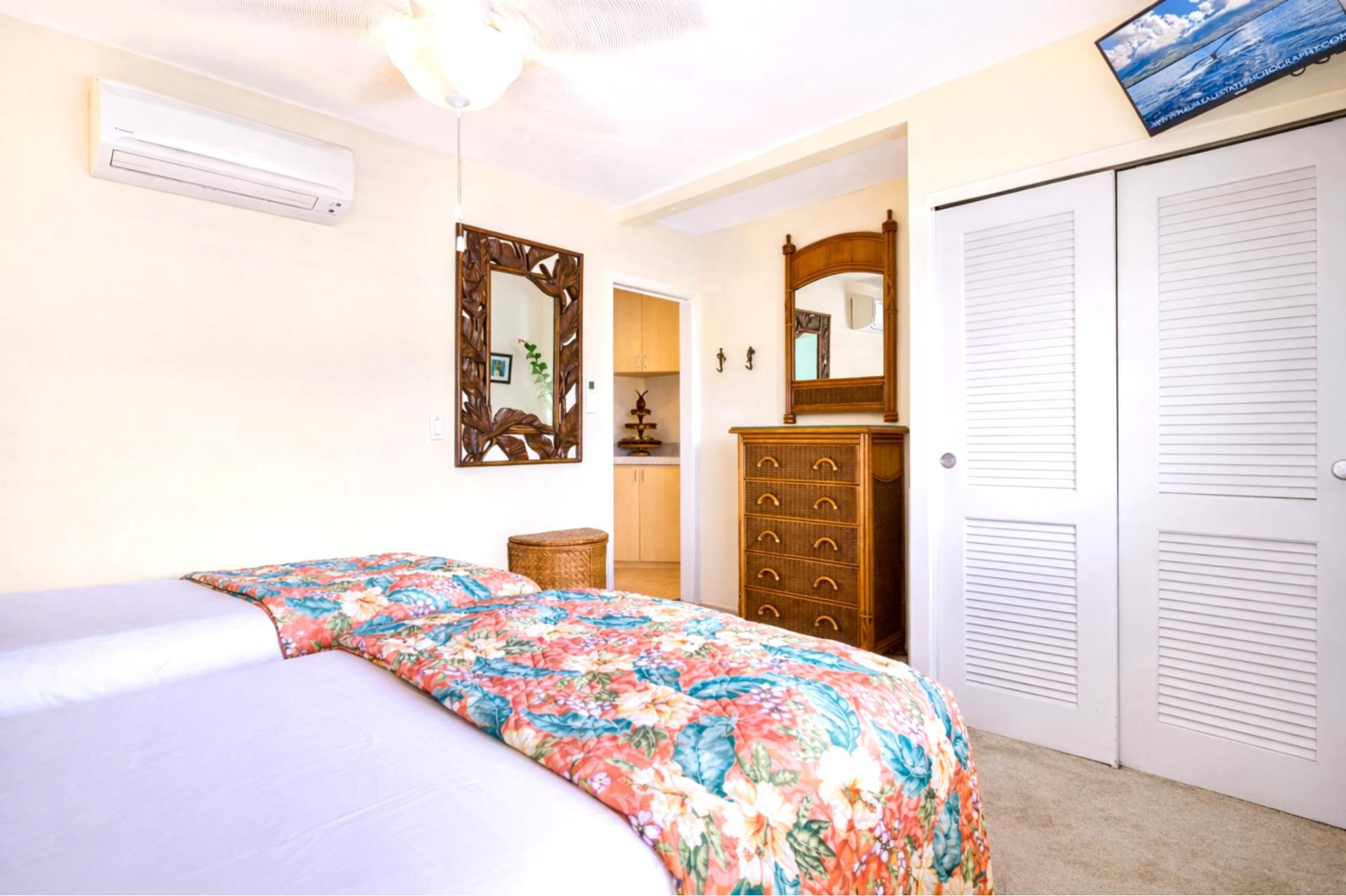 A bedroom with a bed, dresser, wardrobe, and a ceiling fan.