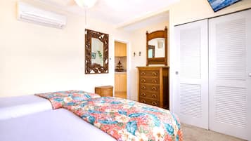 A bedroom with a bed, dresser, wardrobe, and a ceiling fan.