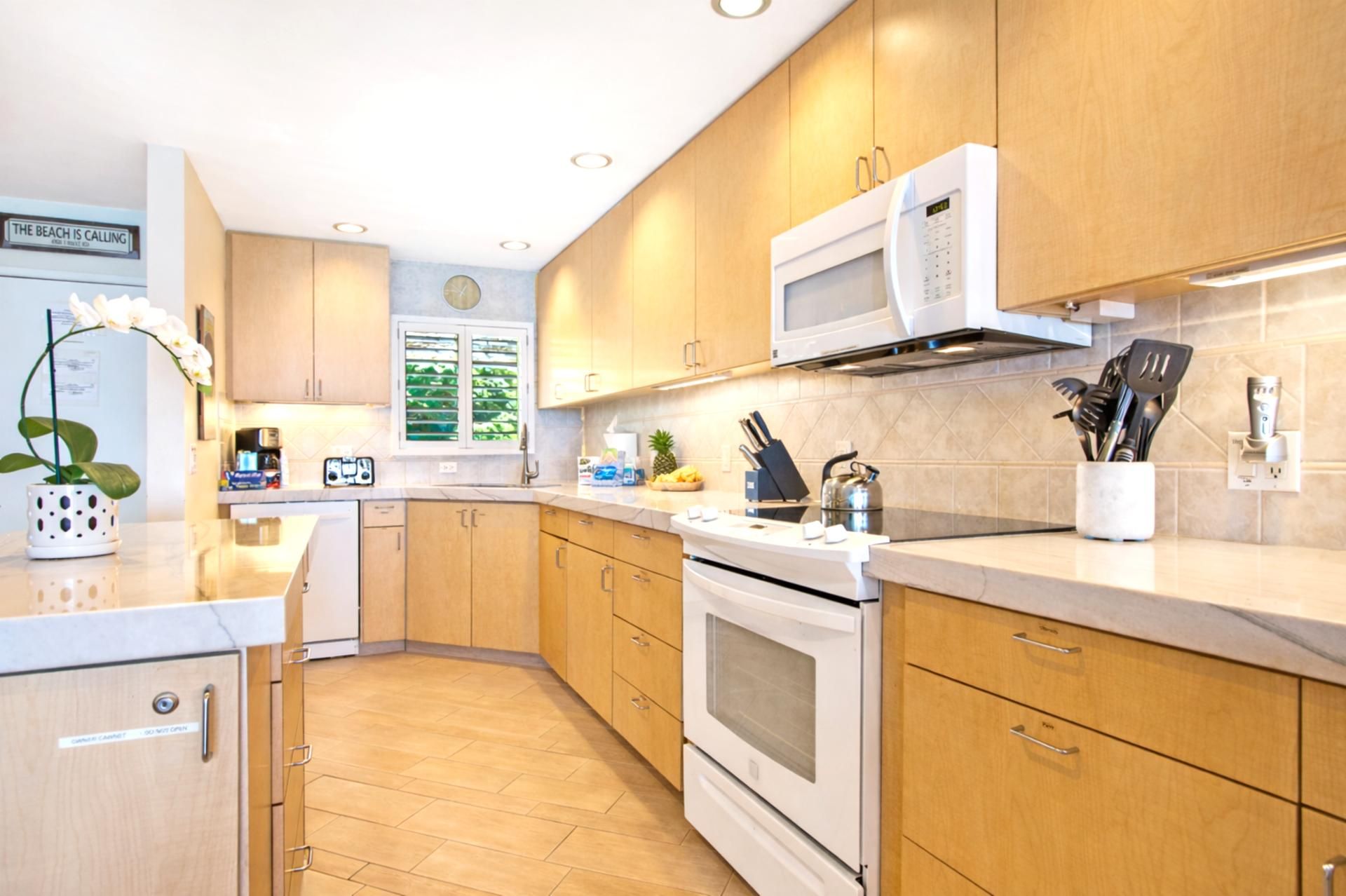 A modern kitchen with wooden cabinets, a microwave, an oven, and a sink.