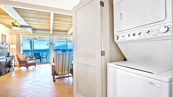 A hotel room with a balcony, a washer and dryer, a dining area with a view, and a ceiling fan.