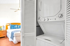 A hotel room with a bed, a nightstand, and a white washing machine.