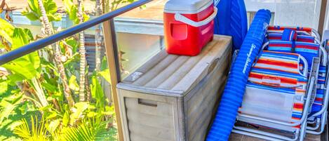 Un balcón con un refrigerador pequeño, una silla azul y un cojín a rayas.