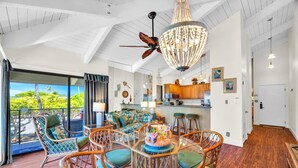 A spacious living area with wicker furniture, a chandelier, and a view of the outdoors. - Napili Point | Ocean View 2 BR Sleeps 6 | Car Incl. w/ 6+ Nights | NAP-C37 by KBM (Lahaina)