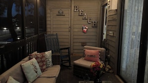 A cozy room with a sofa, a chair, a small table with a bottle, and a wall with 'BEACH' decor. - Experience North Ocean City near the sandy shores (Ocean City)
