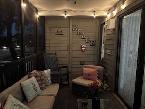 Une pièce chaleureuse avec un canapé, un fauteuil, une petite table sur laquelle se trouve une bouteille, et un mur décoré sur le thème de la « PLAGE ».