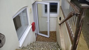 A narrow stairway with a tiled floor leading to a door.