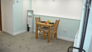 A dining area with a wooden table and chairs, a small table lamp, and a whiteboard on the wall.