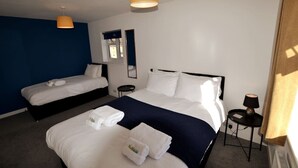Ett hotellrum med två sängar, ett litet bord, en lampa och ett fönster.