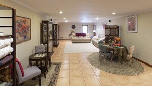 Una sala de estar con un sofá, una mesa de centro y una mesa de comedor con sillas. Hay una estantería y una chimenea.