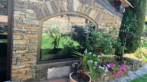 Eine Steinsäule mit einem großen Fenster, das einen Garten und ein Fahrzeug reflektiert.