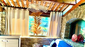 Ein gemütliches Wohnzimmer mit Kamin aus Stein, einem blauen Sofa und einem Holzschrank.