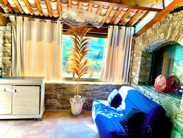 Una sala de estar acogedora con una chimenea de piedra, un sofá azul y un mueble de madera.