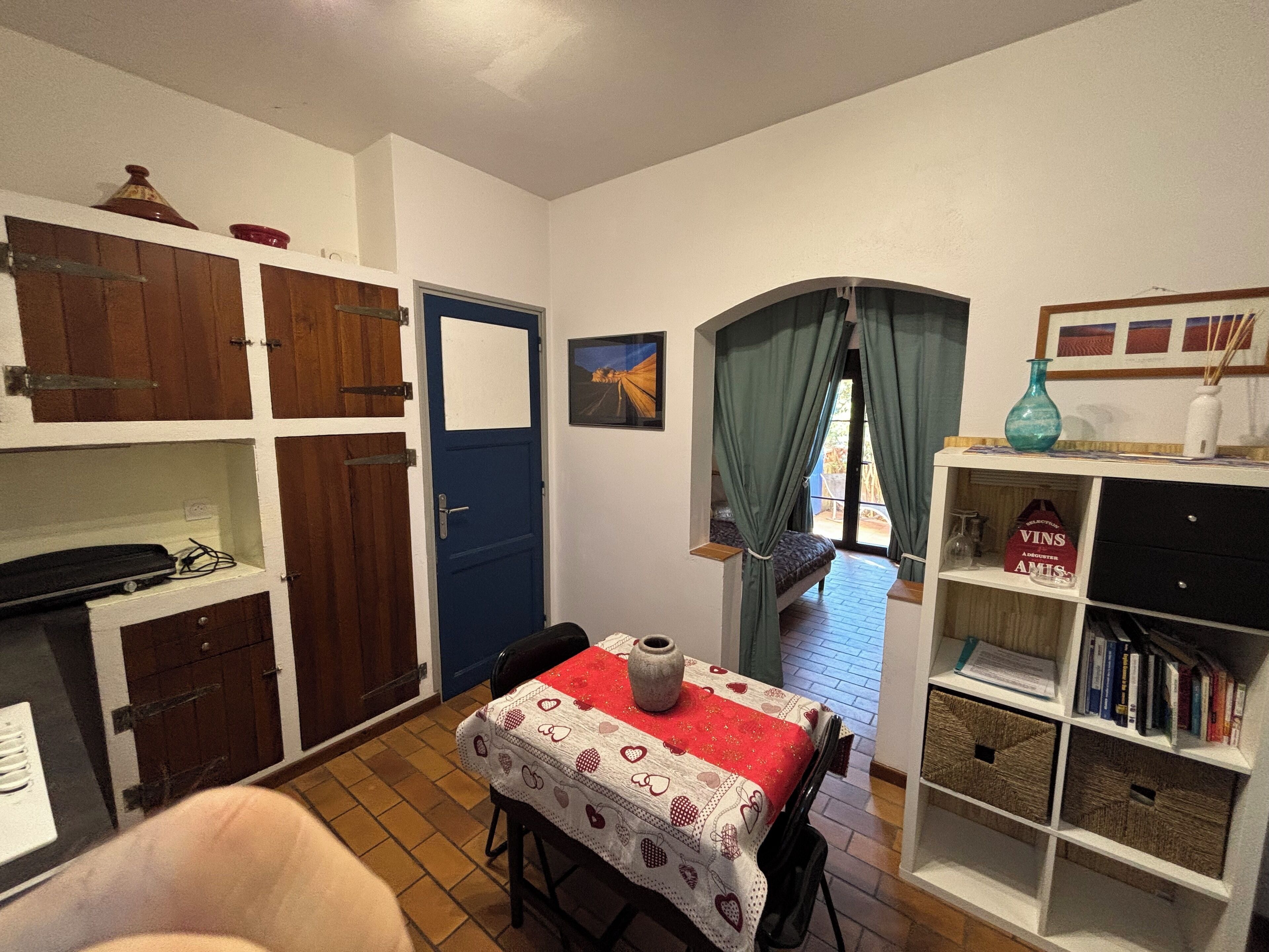 A cozy room with a dining table, a bookshelf, and a blue door.