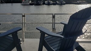 Un terrazzo con due poltrone Adirondack rivolte verso un porto turistico con diverse imbarcazioni ormeggiate.