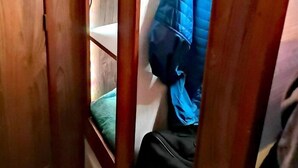 Un couloir étroit en bois, avec un lit superposé et une veste bleue accrochée au mur.