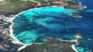 Une vue aérienne d’une zone côtière, avec des eaux turquoise limpides, des plages de sable et une végétation luxuriante.