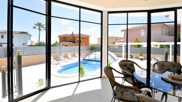 A room with large windows overlooking a swimming pool and neighboring houses. - Beautiful spacious holiday home for families with a big swimming pool and garden - Free Wifi (Marratxi)