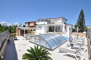 Een modern huis met een overdekt buitengebied, inclusief lounge stoelen en een glazen patio.
