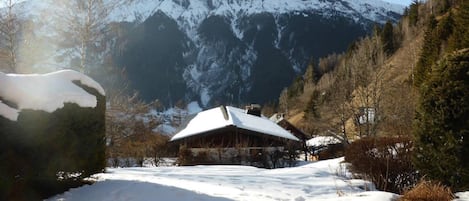 A snow-covered mountain with a wooden building in the foreground.