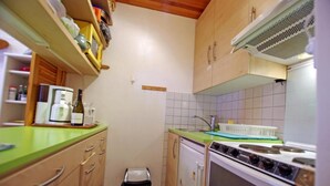 Una cocina compacta con armarios de madera, encimera verde, estufa y lavamanos.