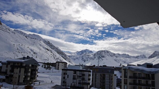 Un pueblo cubierto de nieve con edificios y montañas al fondo.