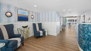 A modern interior with a wooden floor, a blue and white patterned wall, a large painting, and a bar area with a blue marble backsplash. - Pelham on Earle (West Harwich)