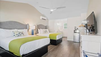 A modern hotel room with two beds, a ceiling fan, a TV, a mini-fridge, and a small kitchenette.