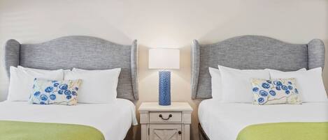 A hotel room with two beds, a nightstand with a lamp, and an air conditioning unit.