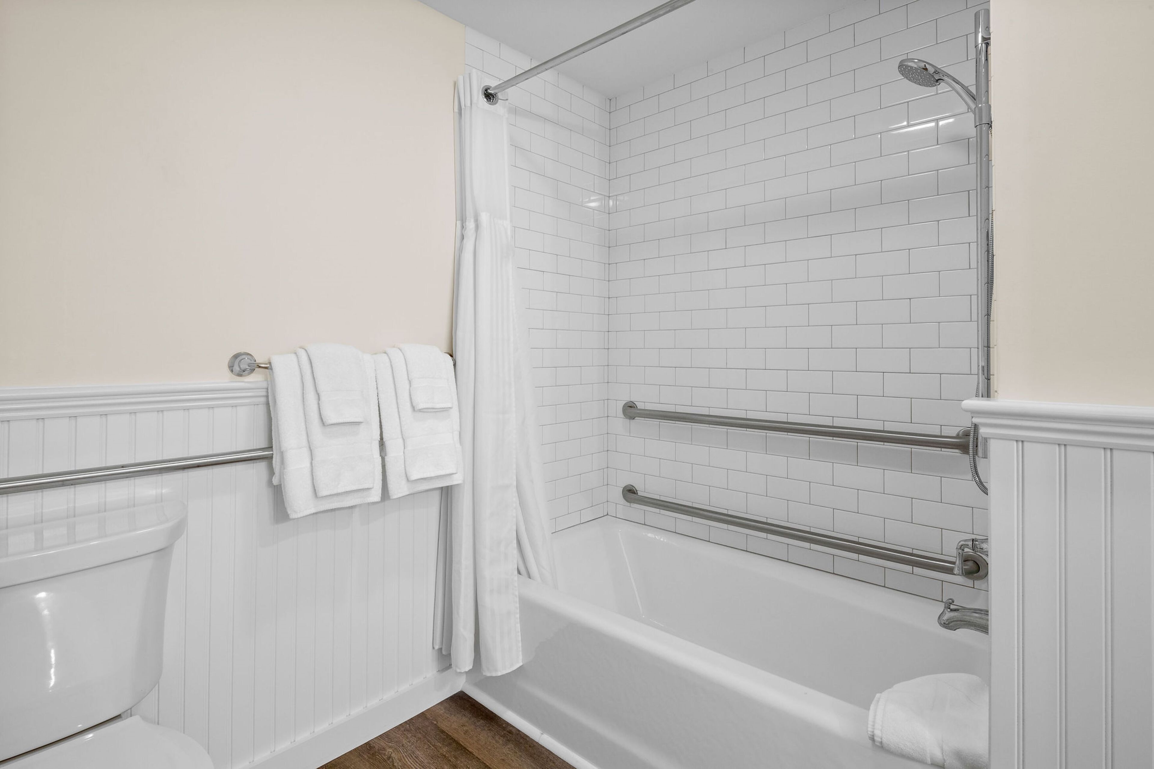 A modern bathroom with a white bathtub, a shower with a glass door, and a toilet.