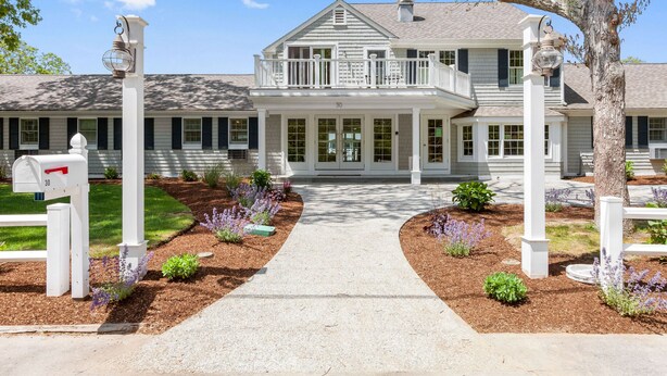 A two-story house with a front porch, a mailbox, and a well-maintained garden. - Pelham on Earle (West Harwich)