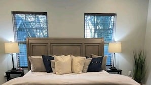 A bedroom with a large bed, two bedside lamps, a nightstand, and a patterned rug.
