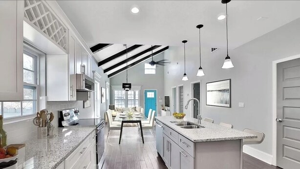 A modern kitchen with granite countertops, a dining area with a table and chairs, and a view of the living room.